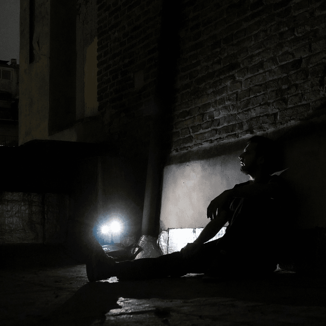 DJ Murlek in a dark, underground-style setting, illuminated by a bright light, embodying raw, hypnotic techno aesthetics